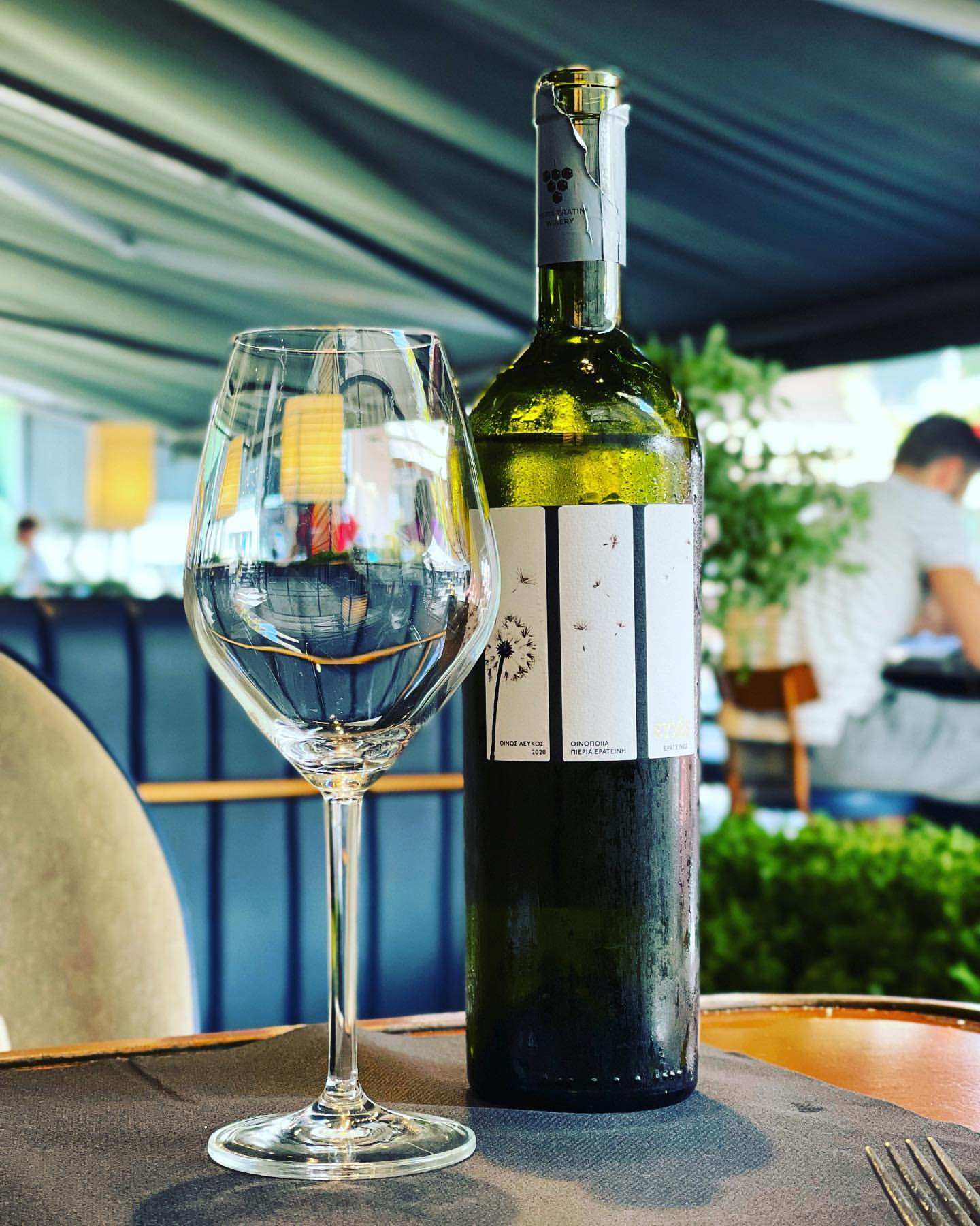 Weißweinflasche PIERIA ERATINI Evches White mit Glas auf einem Tisch in einem Restaurant