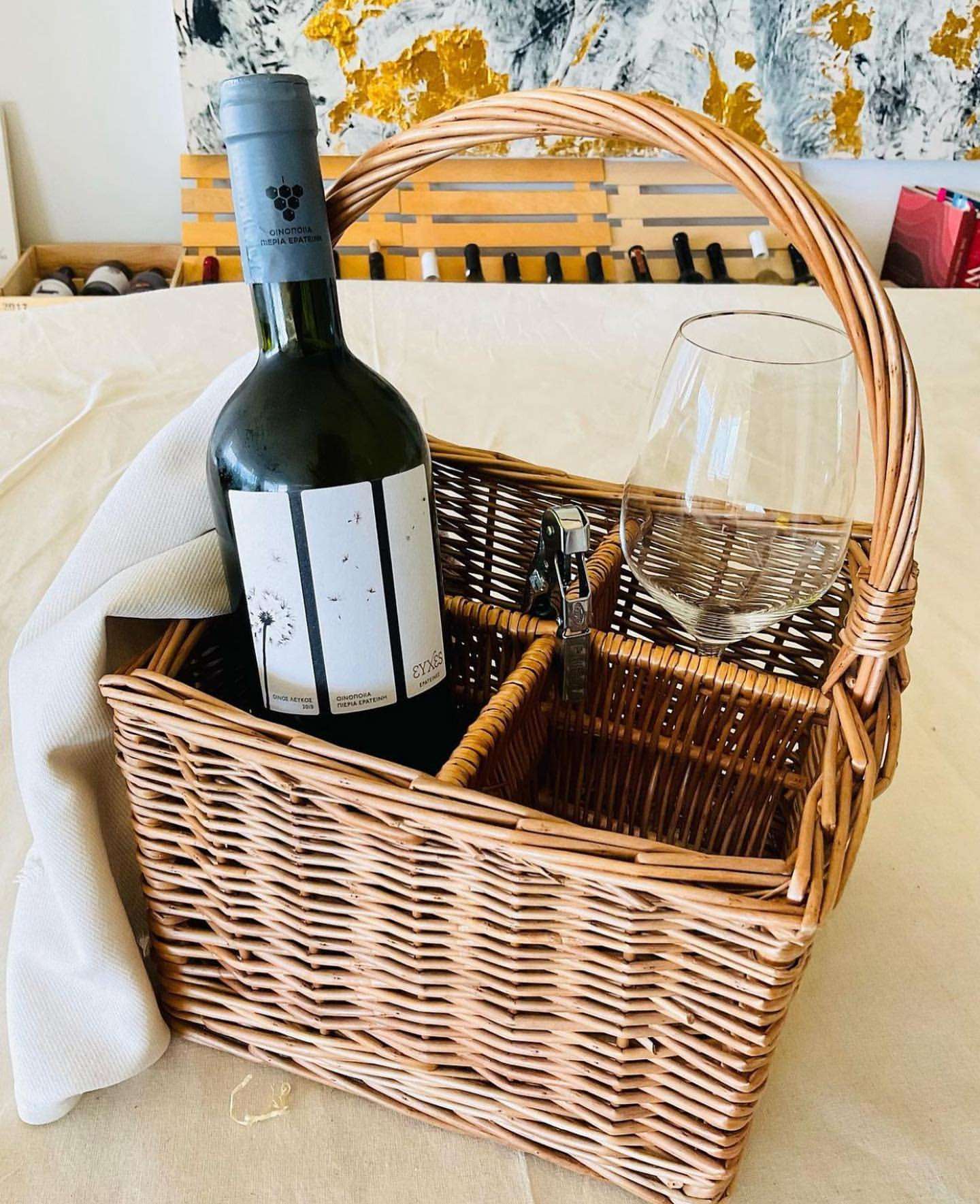 Korb von PIERIA ERATINI mit Flasche Evches White, Glas und Korkenzieher, aus geflochtenem Material.