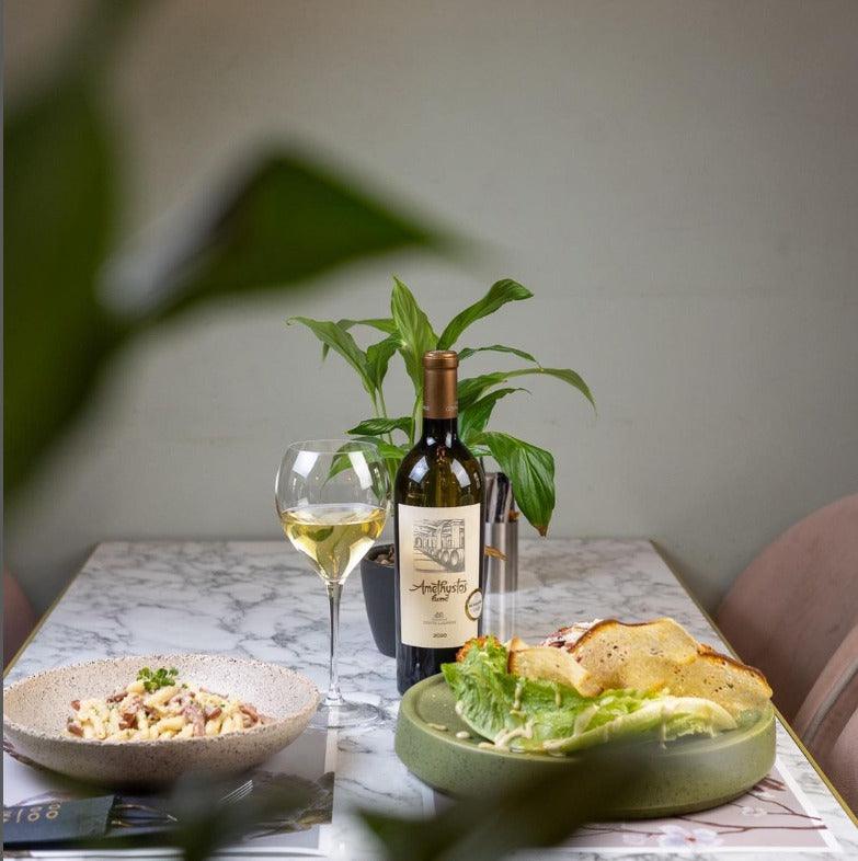 Amethystos Fumé Sauvignon Blanc 2021 Weinflasche mit Glas und Speisen auf Marmorplatte
