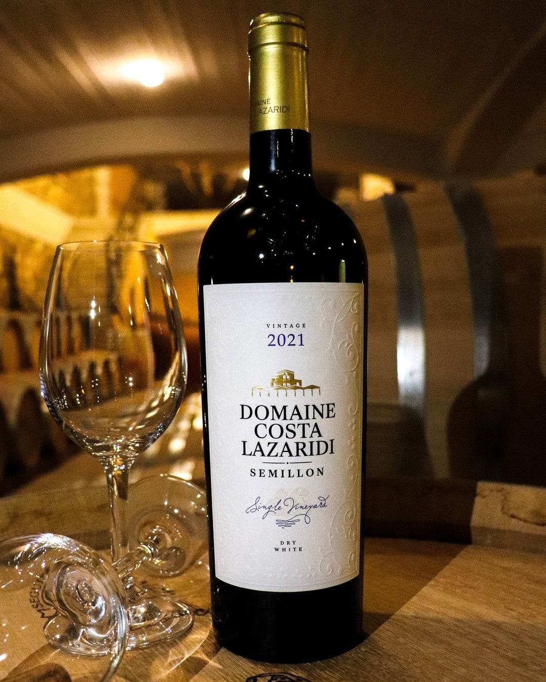Flasche Semillon Domaine Costa Lazaridi Weißwein trocken Jahrgang 2023 mit Weinglas im Fasskeller