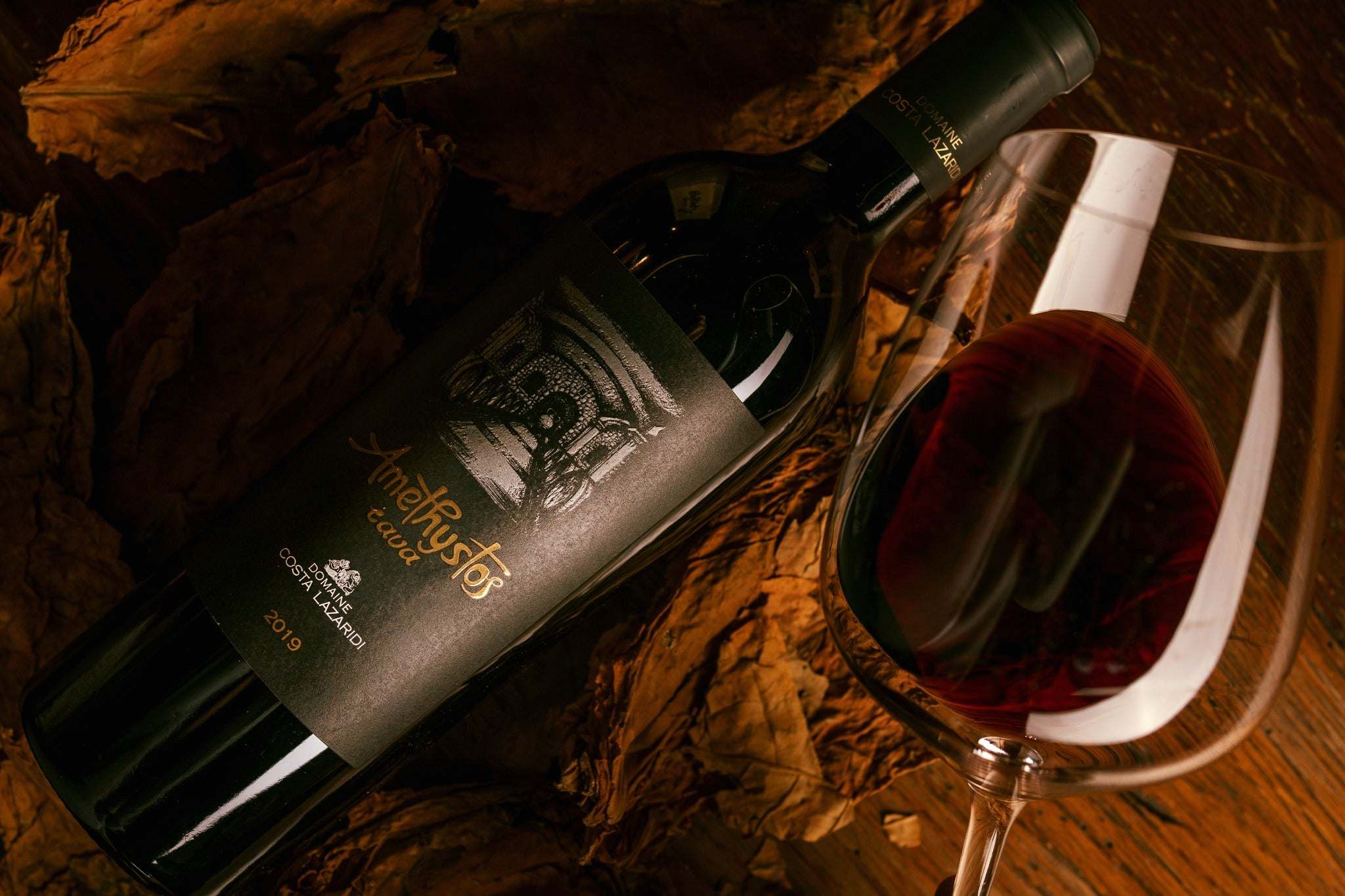 Amethystos Cava Rotwein Flasche mit Wein im Glas auf herbstlichem Hintergrund