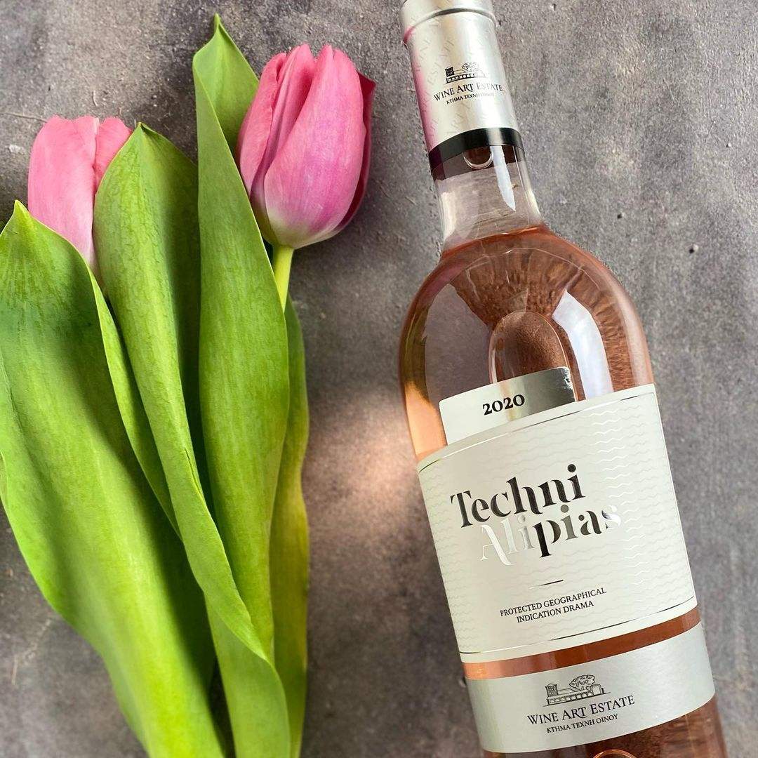 Flasche Techni Rosé Wein 2020 neben rosa Tulpen auf grauem Hintergrund