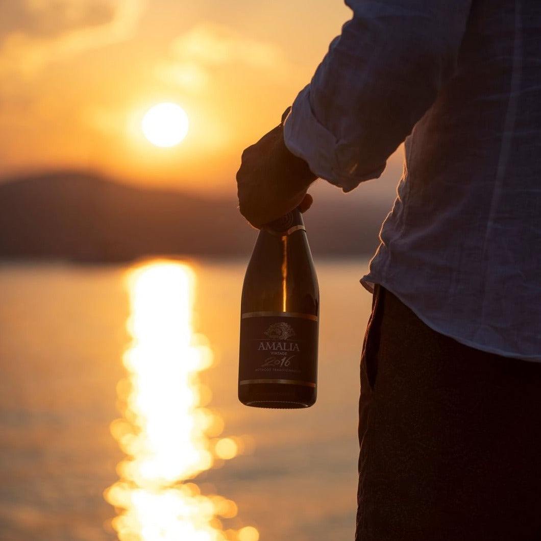 Amalia Brut Schaumwein Flaschengärung Moscofilero bei Sonnenuntergang am Wasser