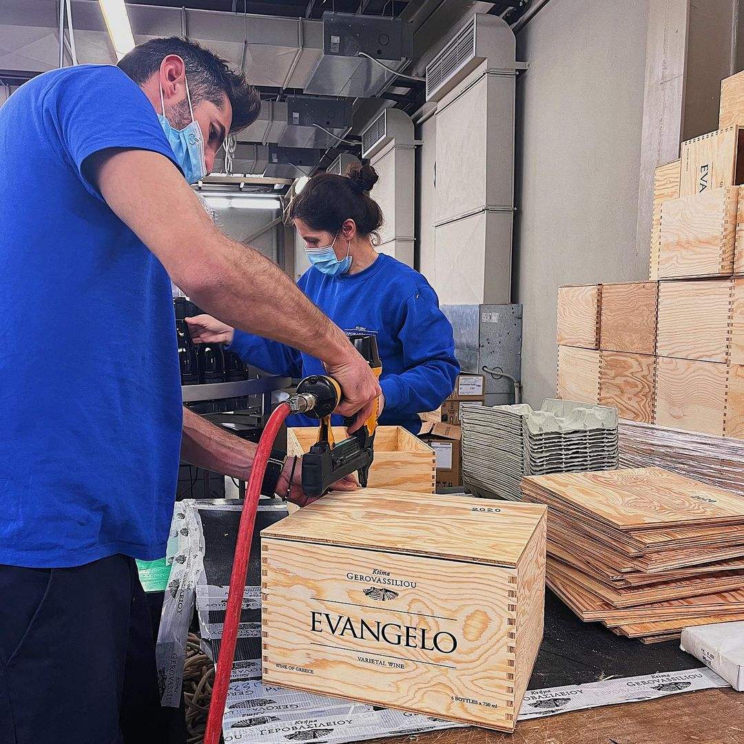 Verpackung Gerovassiliou Evangelo Wein in Holzkisten mit Mitarbeitern in Schutzmasken im Weinkeller