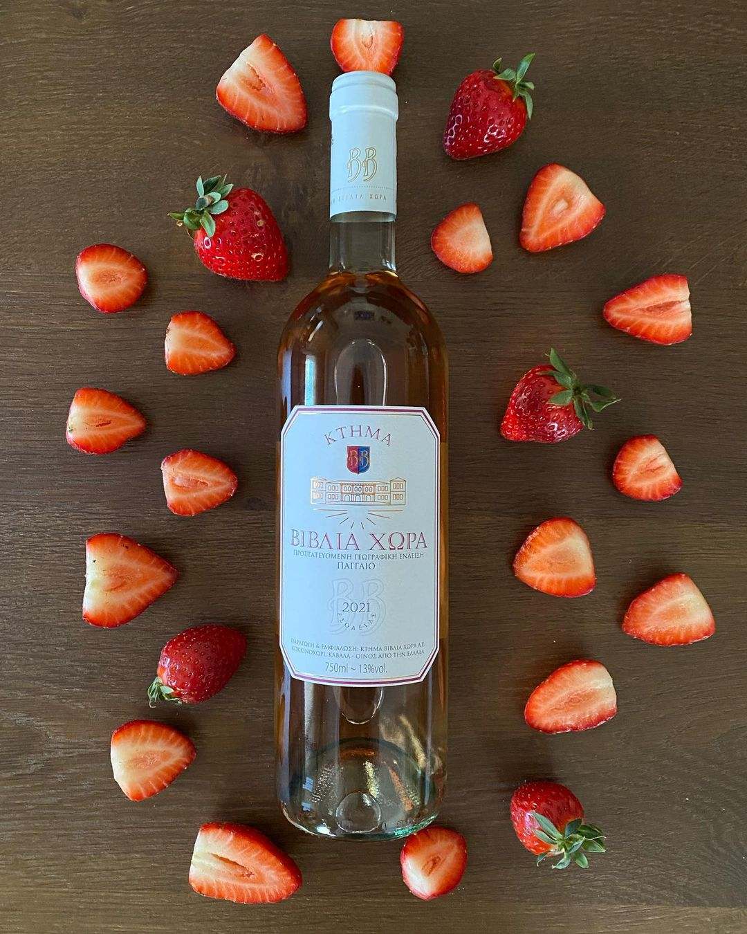 Flasche Biblia Chora Rosé 2024 Syrah mit frischen Erdbeeren auf Holztisch