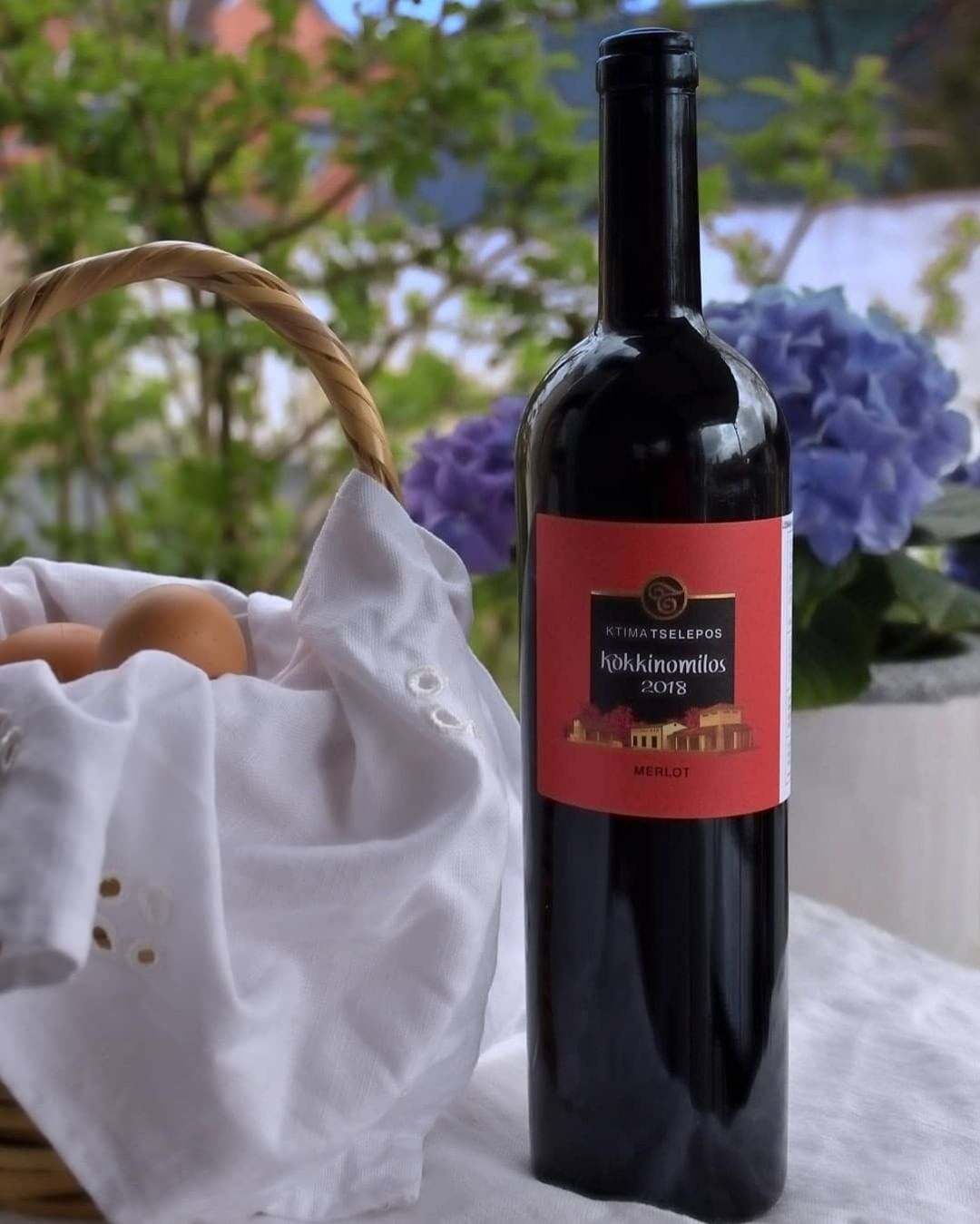 Flasche Tselepos Kokkinomylos Merlot 2022 aus Arkadien mit rotem Etikett und Weinkorb im Hintergrund