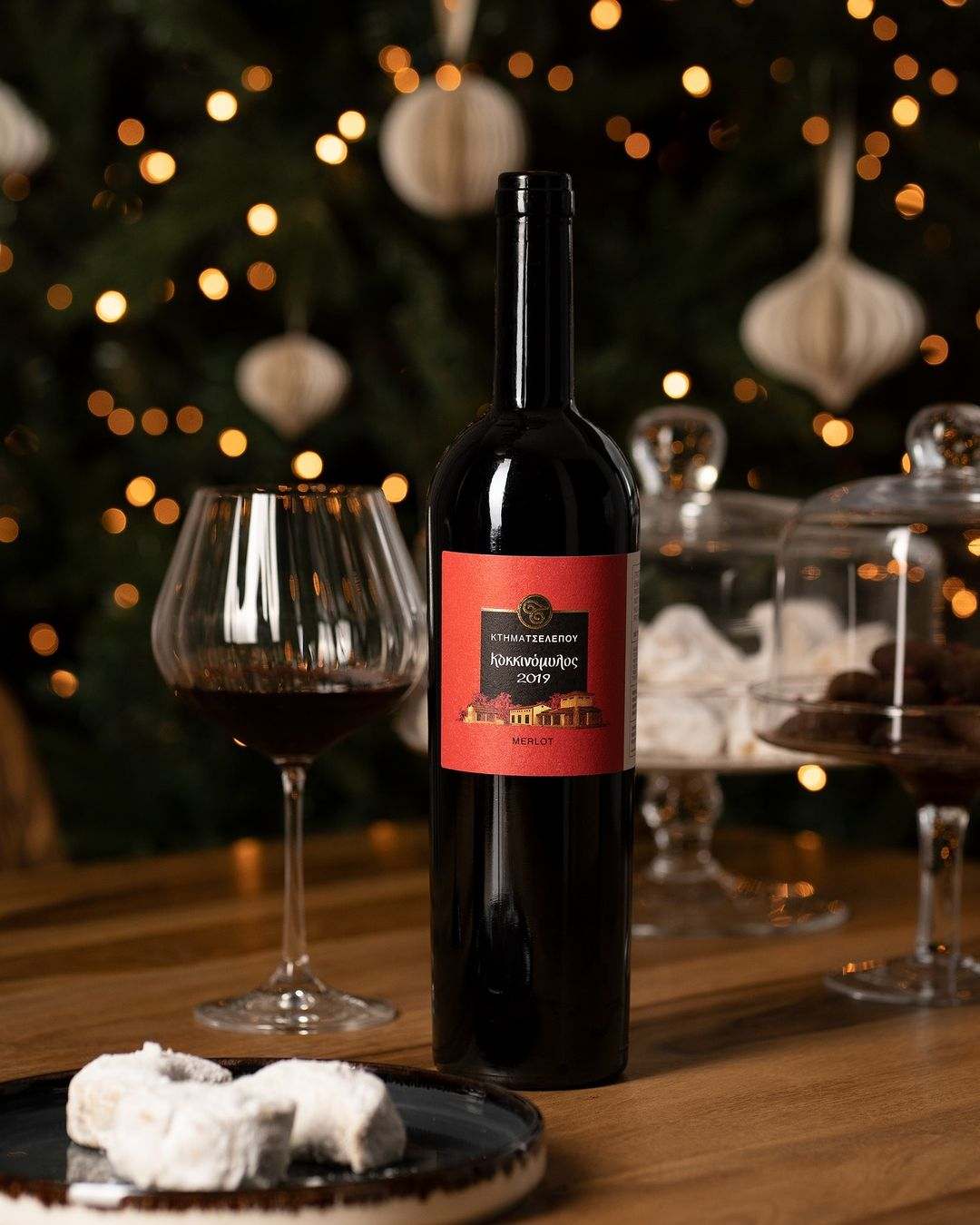 Flasche Tselepos Kokkinomylos Merlot 2022 mit Glas vor Weihnachtsdeko