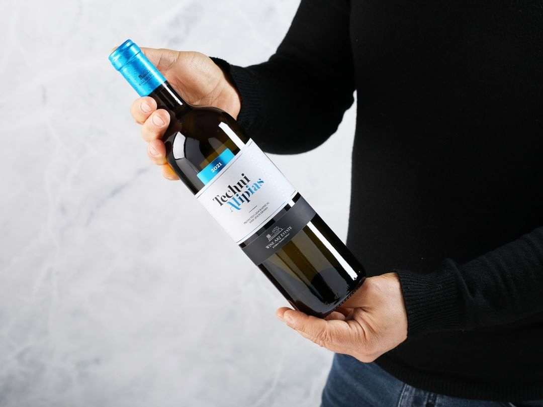 Mann hält Techni White Weißweinflasche aus Drama PGI, 2024er Jahrgang, Sauvignon und Assyrtiko, 13% Vol.