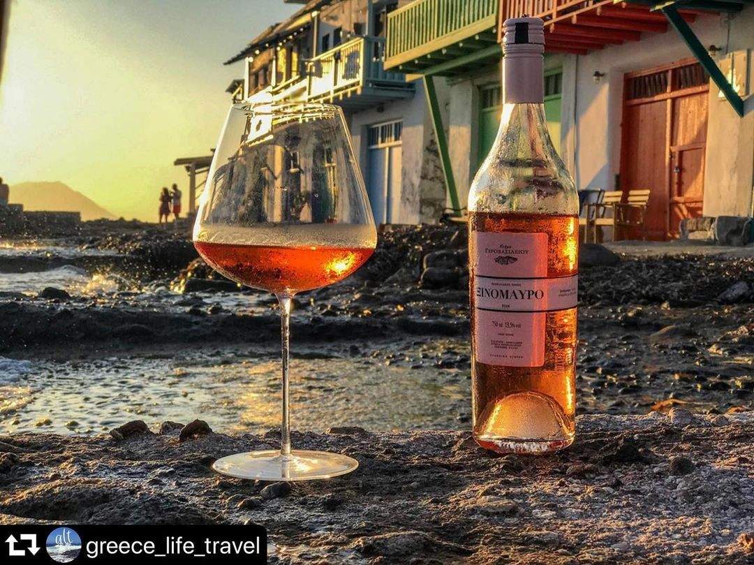 Gerovassiliou Rosé Weinflasche und Glas mit zartrosa Wein am Meer bei Sonnenuntergang