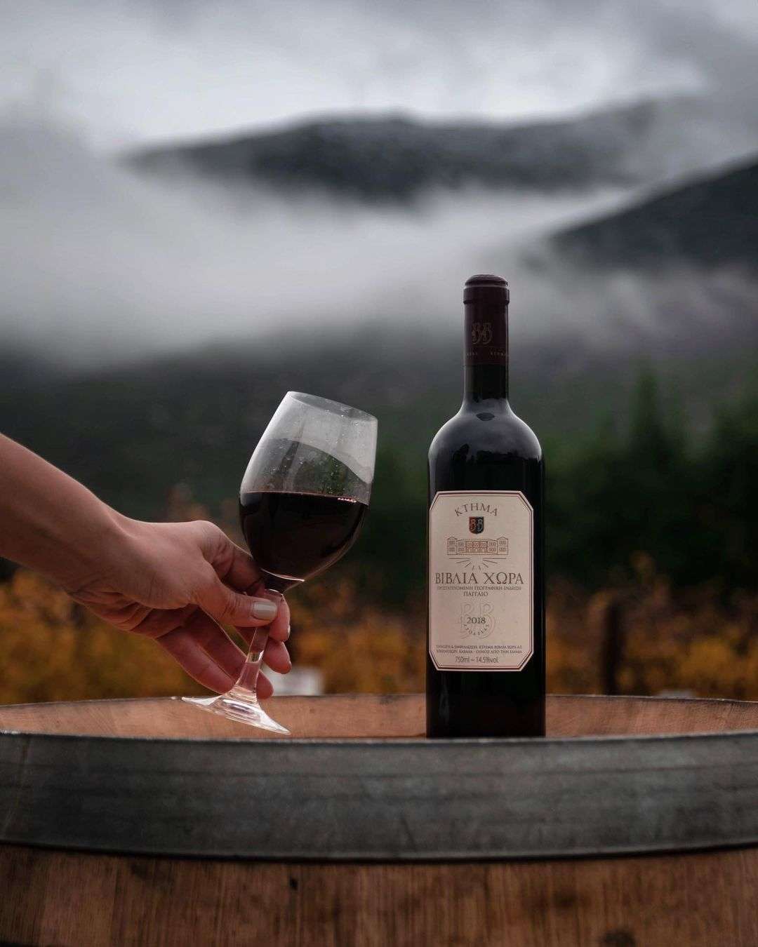 Biblia Chora Rotwein Flasche mit Glas vor nebliger Berglandschaft