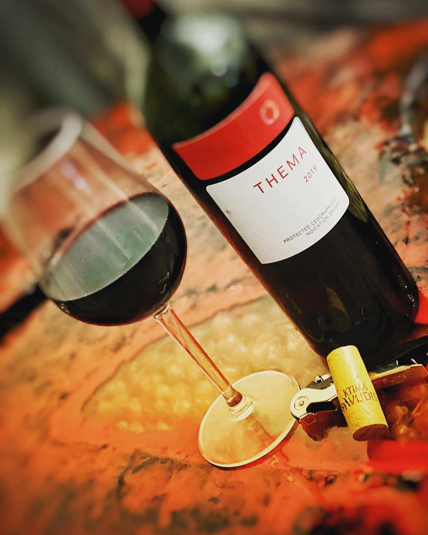 Pavlidis Thema Rot Weinflasche und Glas mit tiefrotem Wein aus Drama, Griechenland, Syrah und Agiorgitiko gelesen 2022, Holzfassausbau, elegante Fruchtnoten von Kirsche und Pflaume.