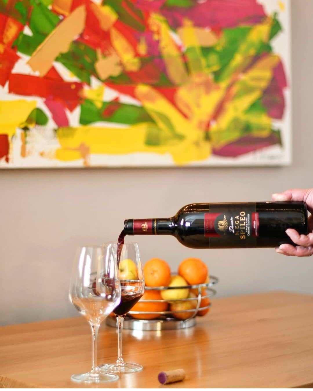 Mega Spileo Cabernet Sauvignon Rotweinflasche gießt Wein in Glas mit Obstschale im Hintergrund