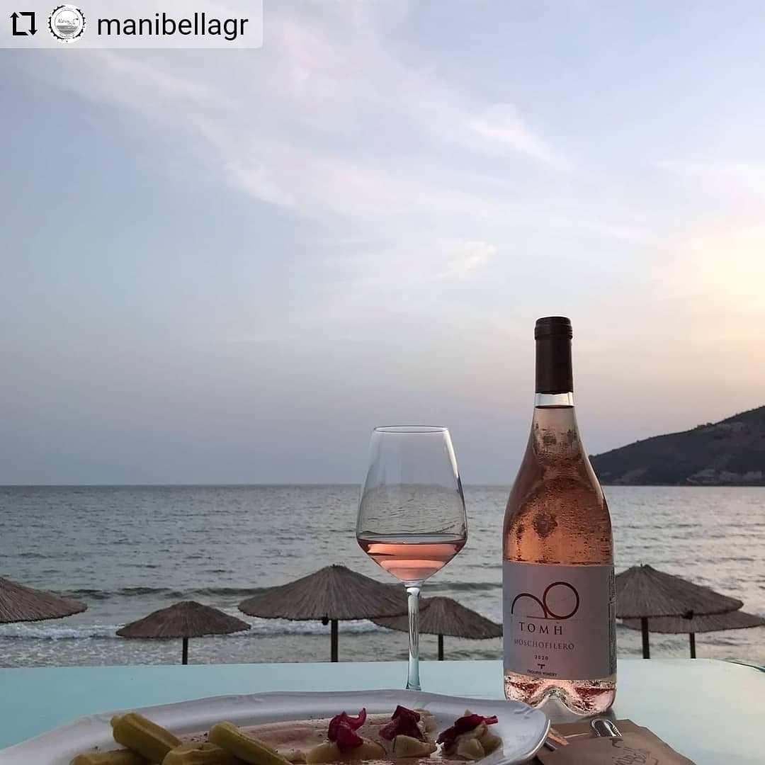 Troupis Tomi Rosé Weinflasche und Glas mit rosé Wein am Strand mit Meerblick und Sonnenuntergang