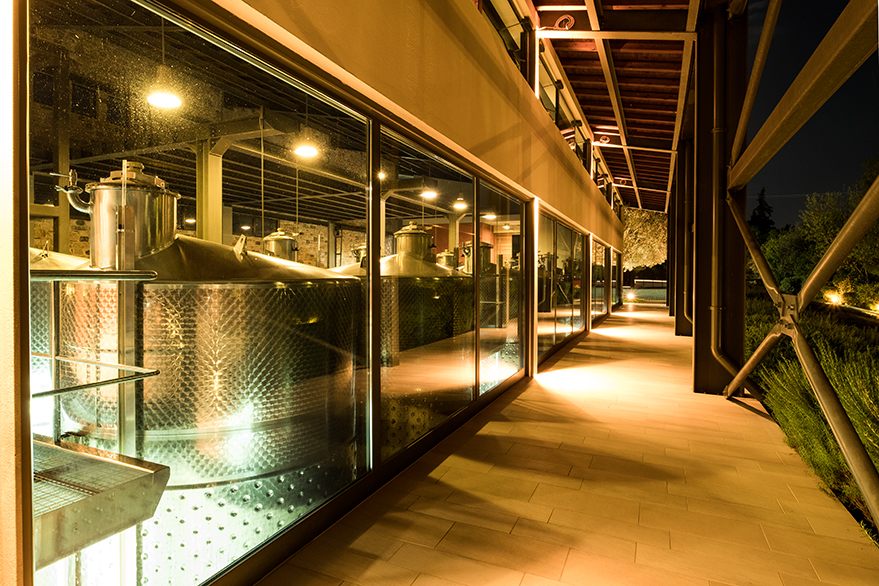 Brauerei mit großen, silbernen Gärtanks und beleuchtetem Innenraum bei Nacht
