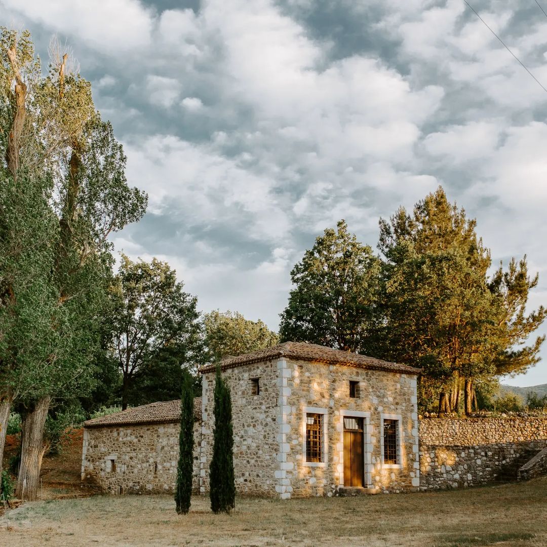Steinernes Ferienhaus mit Holzveranda und Bäumen im Hintergrund