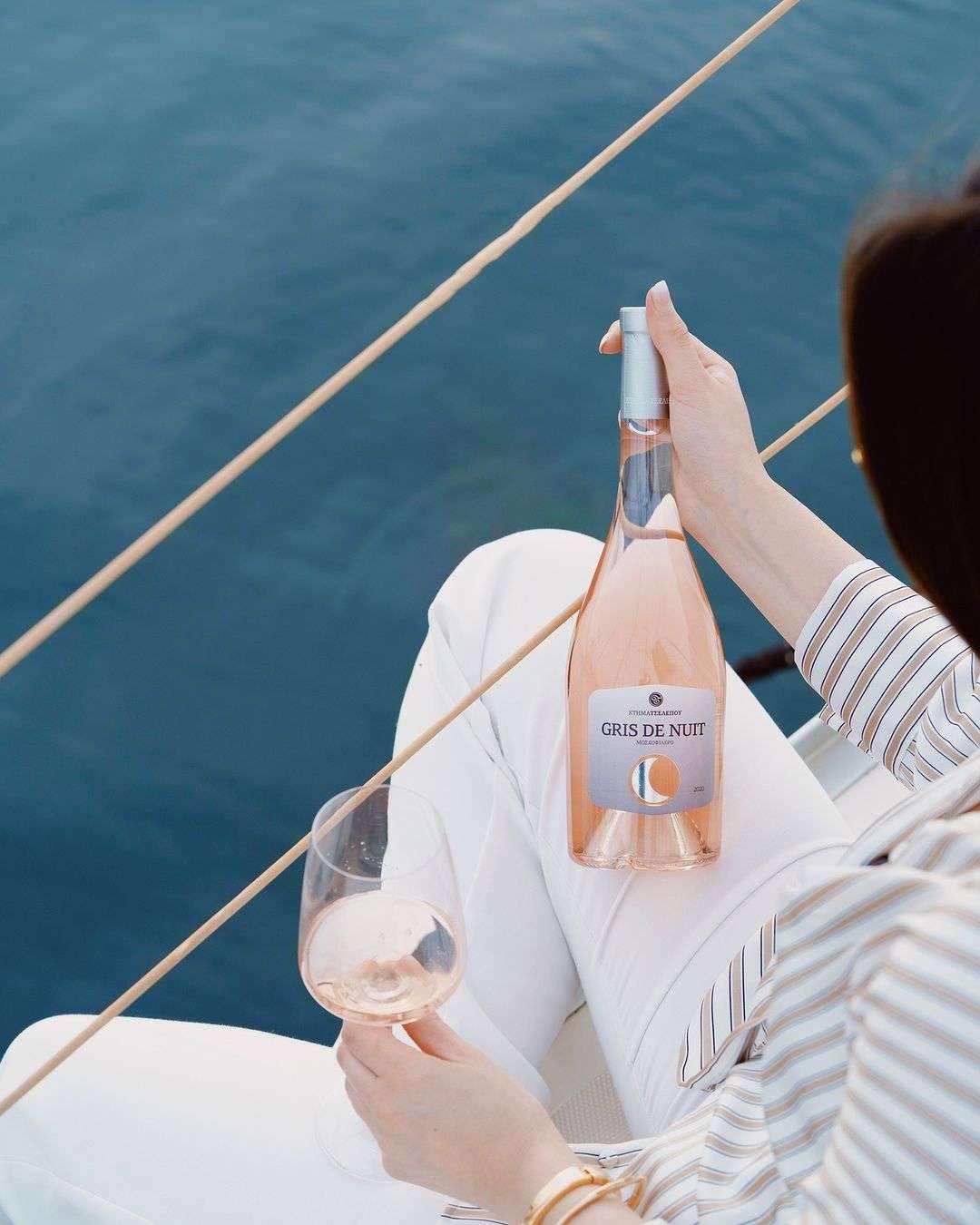 Tselepos Gris de Nuit von Domaine Tselepos in rosé mit Glas auf einem Boot am Wasser