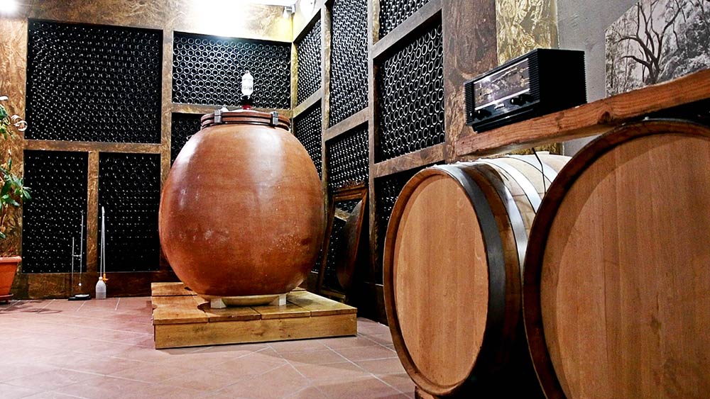 Tonkugel für Weinlagerung aus Terrakotta mit Holzregal und Eichenfässern im Hintergrund