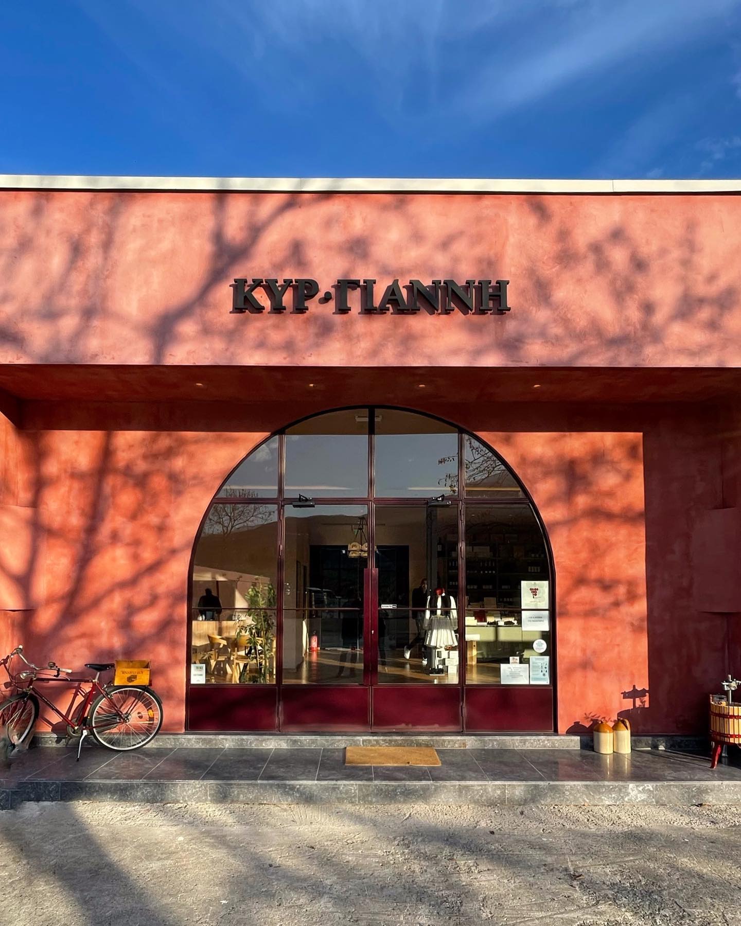 Ladenfassade von KYP-TIANNH mit großen Fenstern und roter Wandfarbe, Fahrrad vor dem Geschäft.