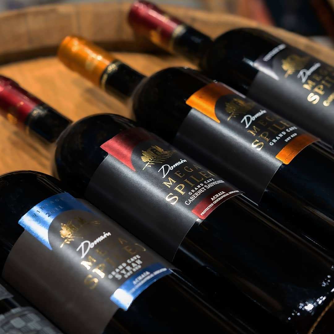 Mega Spileo Syrah Weinflasche mit schwarzem Etikett und farbigen Akzenten auf Holzfass liegend